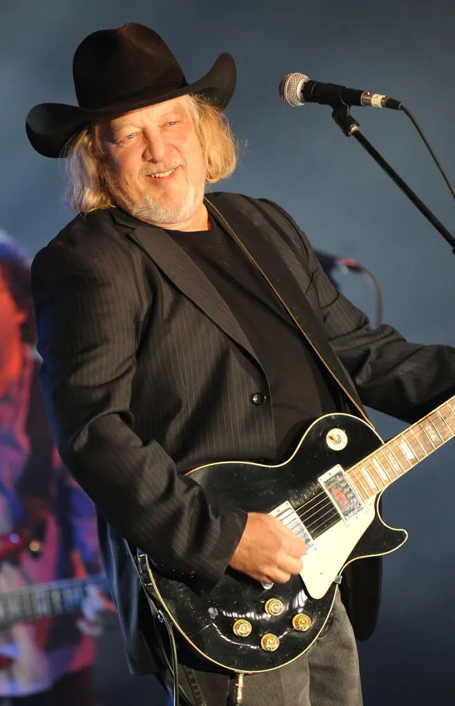 Singer-songwriter John Anderson performs with a black electric guitar.