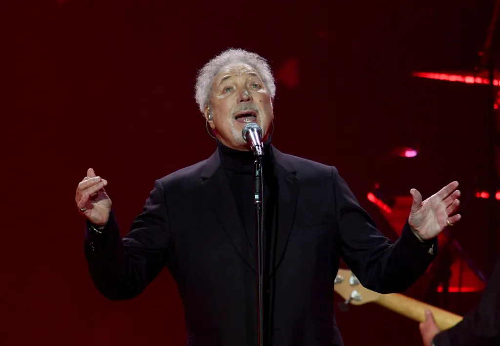 Sir Tom Jones sings into a microphone on stage.