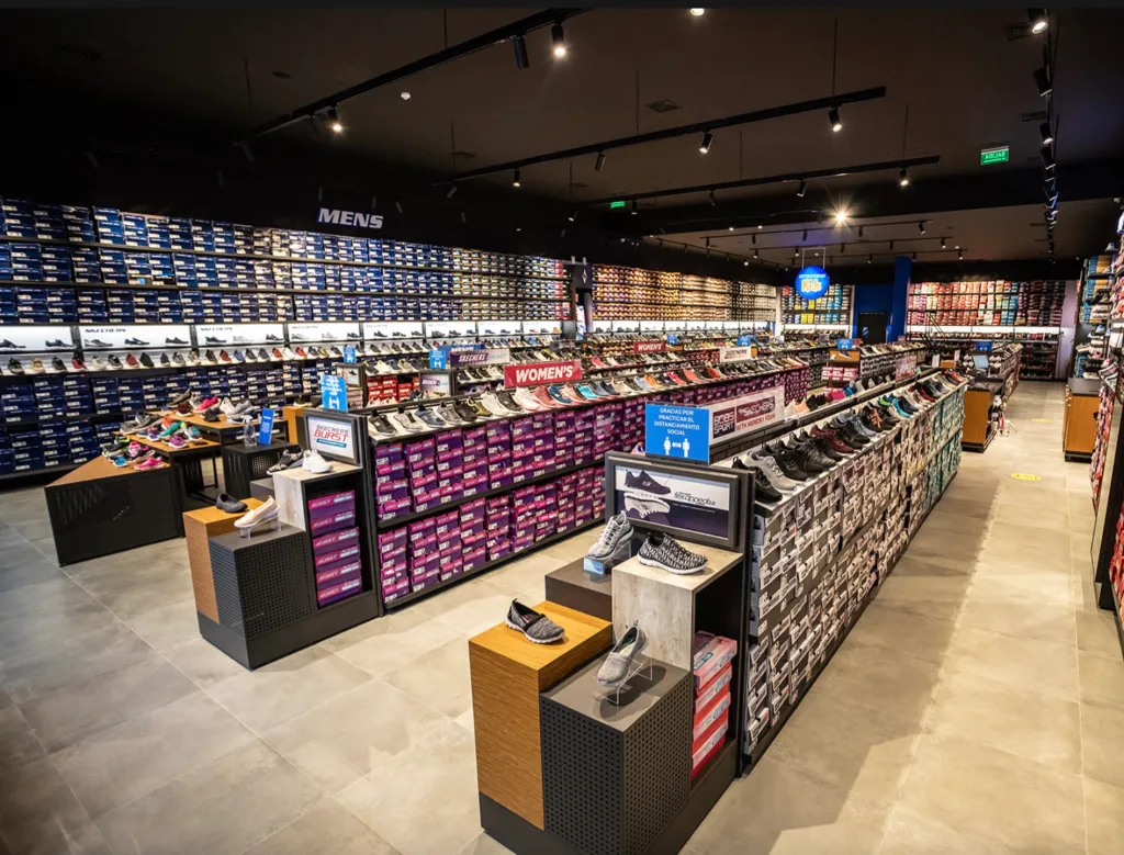 Interior view of a Skechers retail store featuring custom fixtures by Artitalia Group, displaying rows of shoes and shoeboxes.