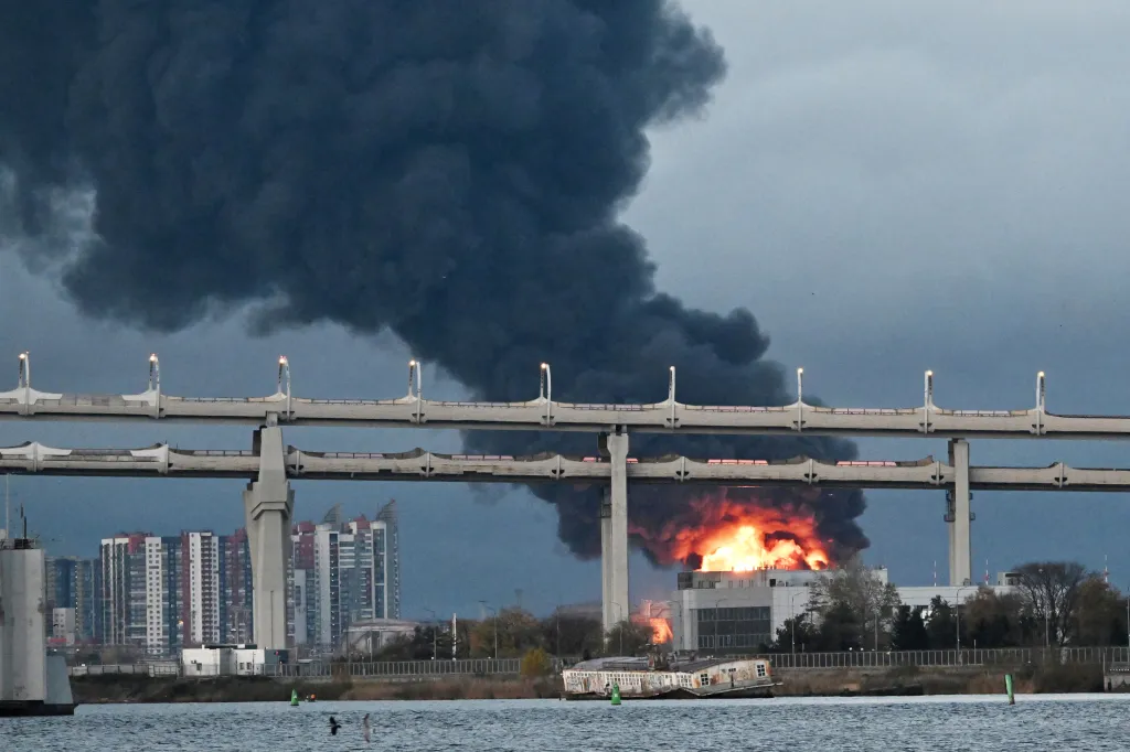 Thick black smoke and flames rise from an oil terminal in Saint Petersburg behind an elevated highway and residential buildings.