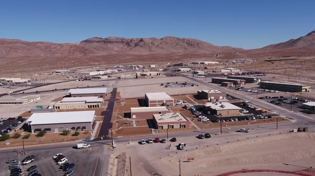 Aerial view of the Special Technologies Laboratory facility, surrounded by a vast desert landscape and mountains.
