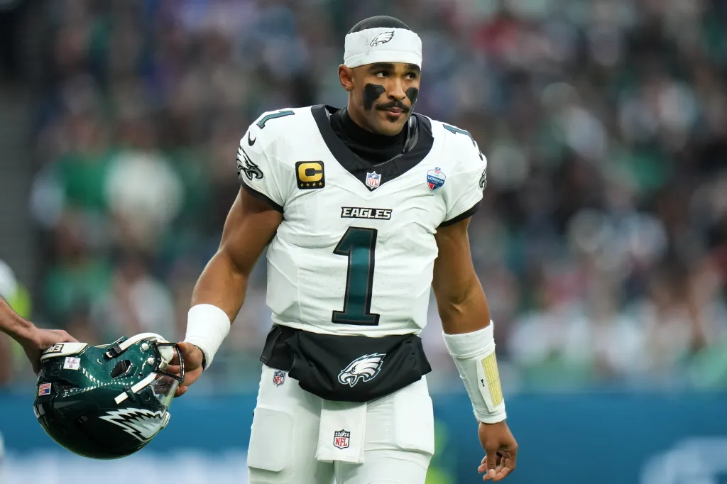 Philadelphia Eagles quarterback Jalen Hurts stands on the field, holding his helmet, during a game against the Jacksonville Jaguars.