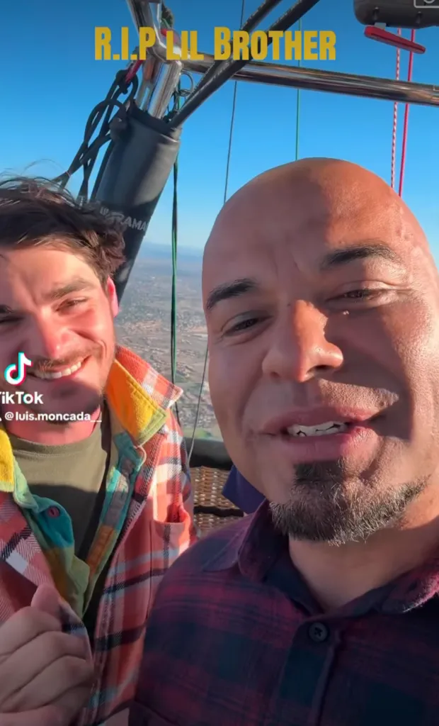 Two men, Luis Moncada on the right and RJ Mitte on the left, smiling together inside a hot air balloon basket with a landscape visible in the background, featuring yellow text that reads 