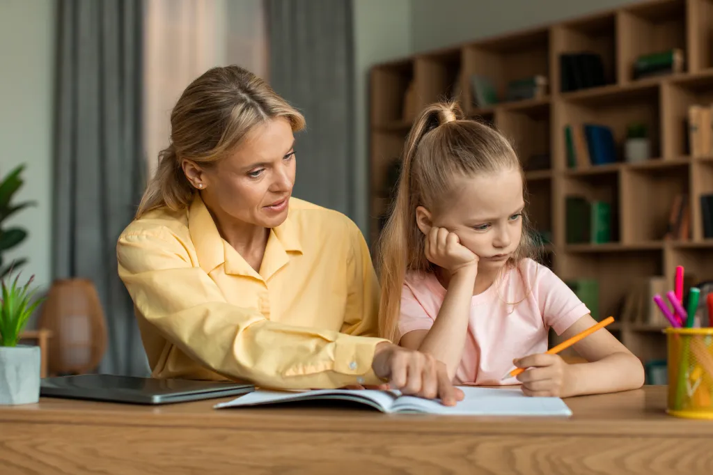 A strict mother scolding her unmotivated daughter while studying together at a desk.