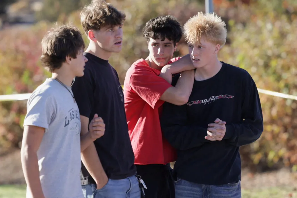Students from the neighborhood stand on the sidewalk at the scene following a shooting at Silver Rail Elementary School in Bend, Oregon.