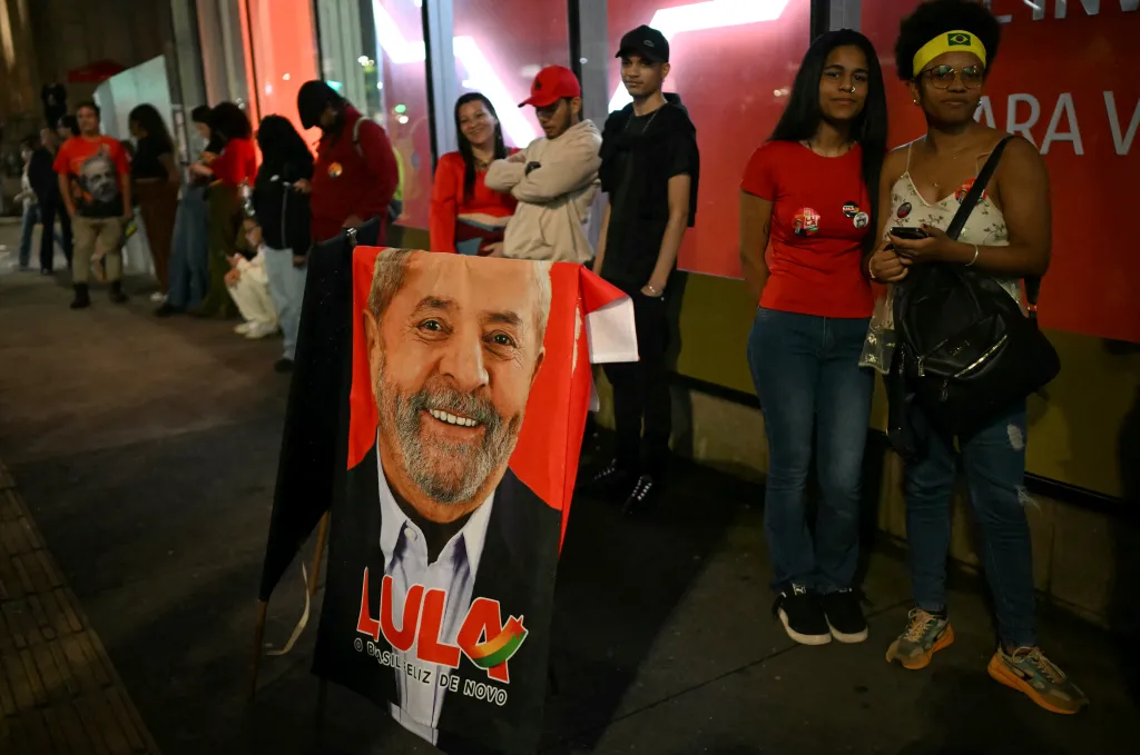 Supporters of Luiz Inacio Lula da Silva gather around a campaign banner displaying his face in Sao Paulo.