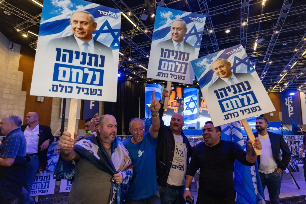 Likud Party supporters hold campaign signs featuring Benjamin Netanyahu at an election-night event.