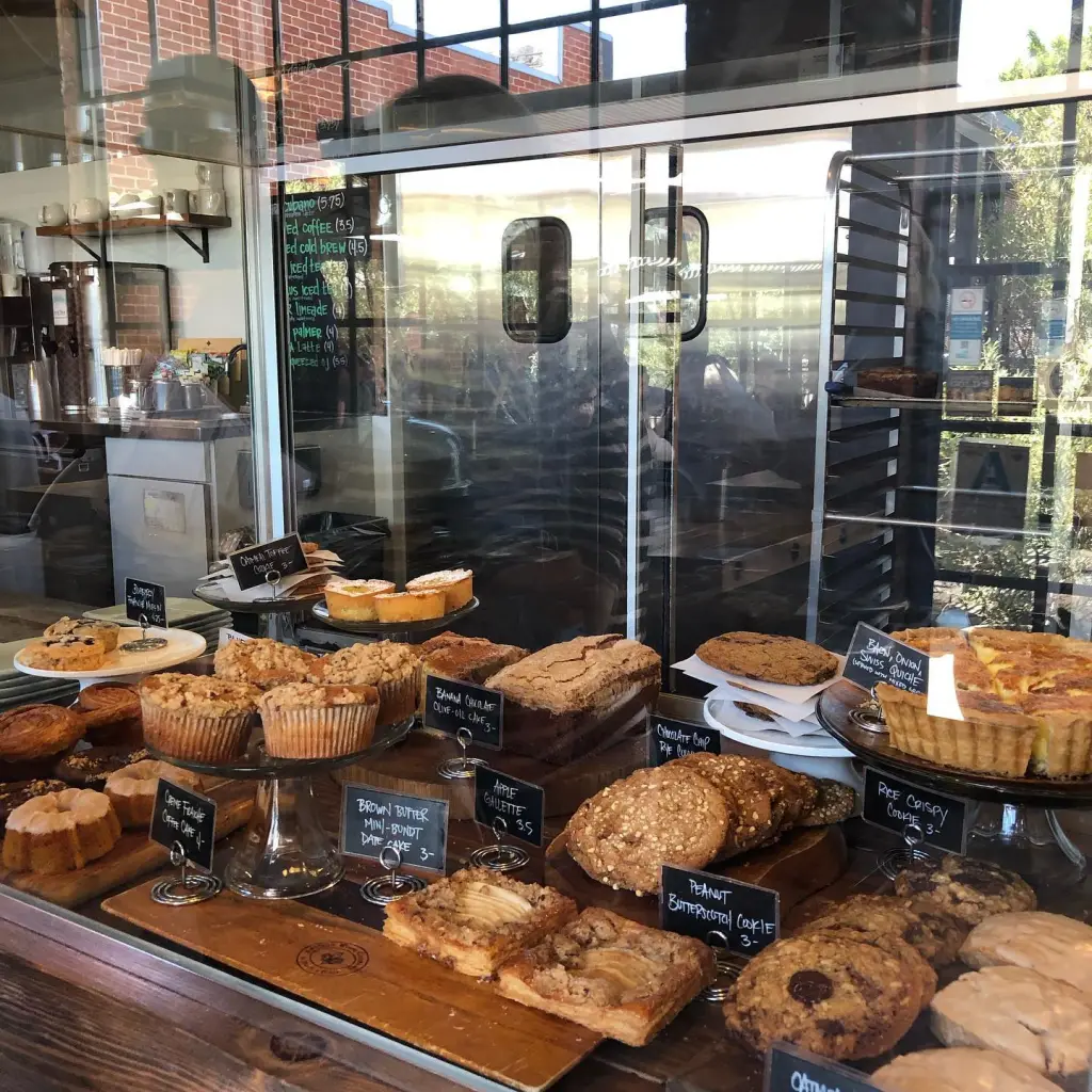 Glass display case at Sycamore Kitchen filled with various pastries, muffins, cakes, and quiche.