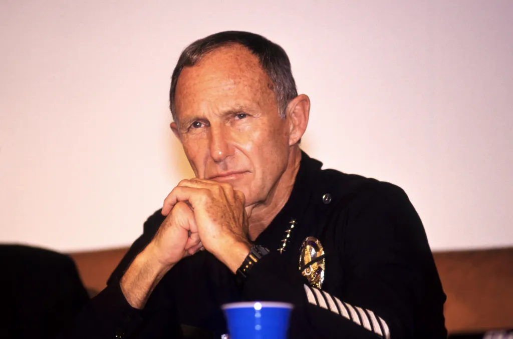 LAPD Chief Daryl Gates listening with clasped hands during a news conference in the aftermath of the riots.