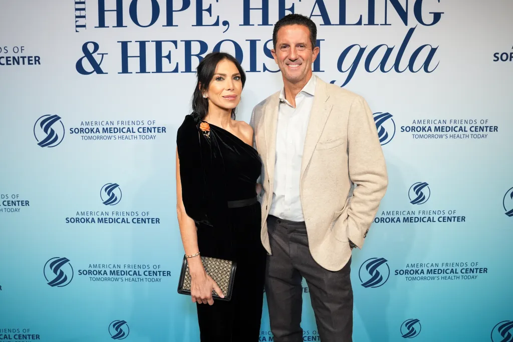 Tanya Zuckerbrot and Anthony Westreich pose together in front of a branded event backdrop.
