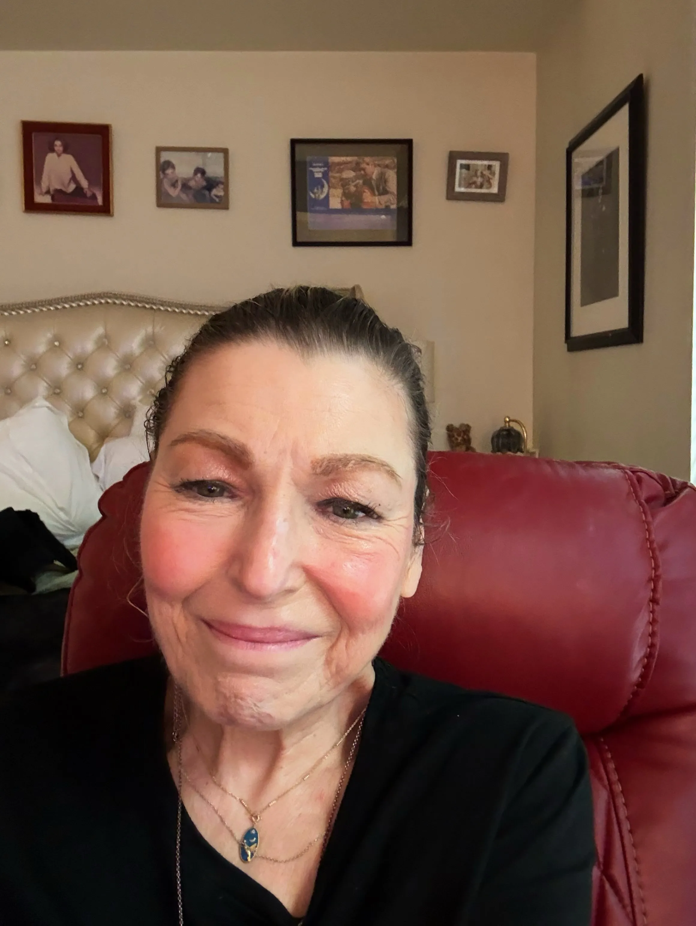 Selfie of Tatum O'Neal smiling while seated in a red chair.