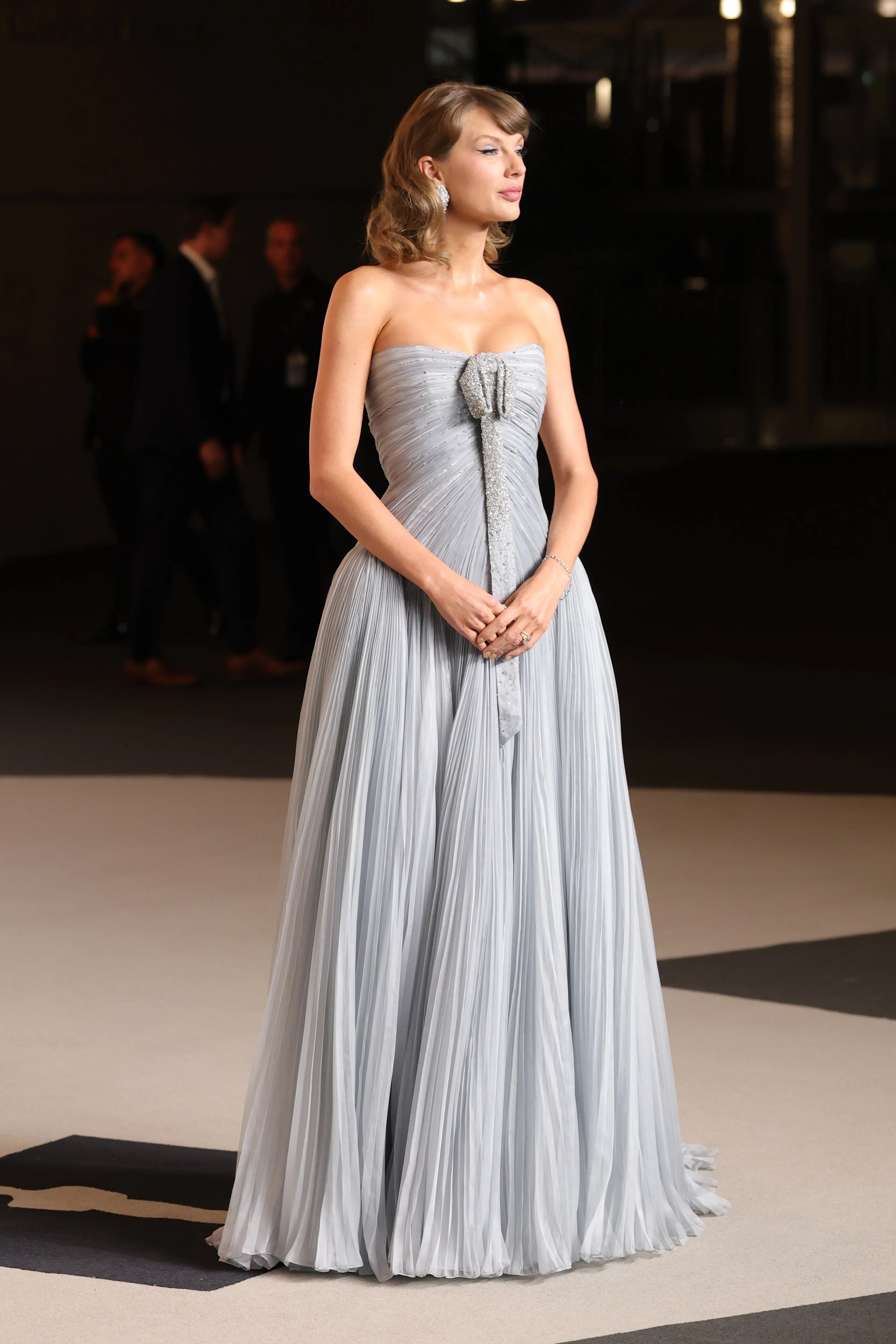 Taylor Swift attends the Academy Museum Gala wearing a strapless, light blue pleated gown with a silver bow detail.