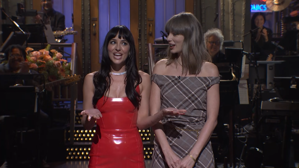 Dakota Johnson and Taylor Swift stand on stage during the Saturday Night Live monologue.