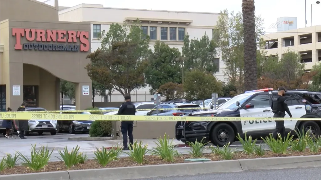Police investigate a crime scene outside a building with yellow police tape blocking the area.