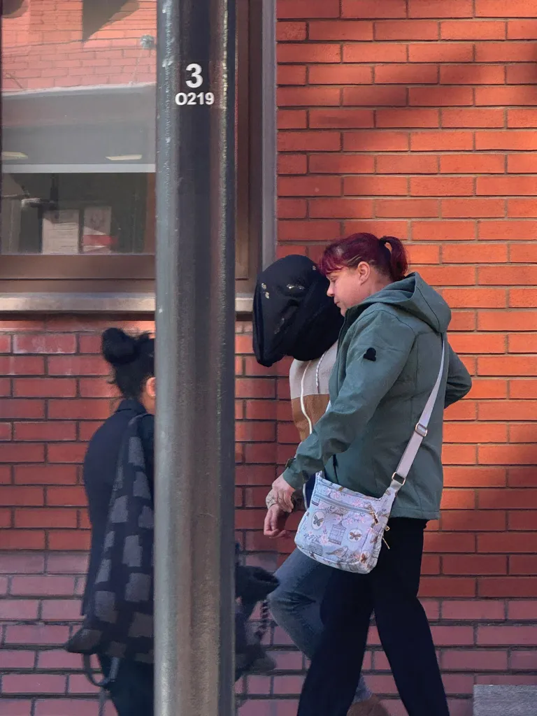 Thomas Mikaelson walks outside Leeds Crown Court with his head covered.