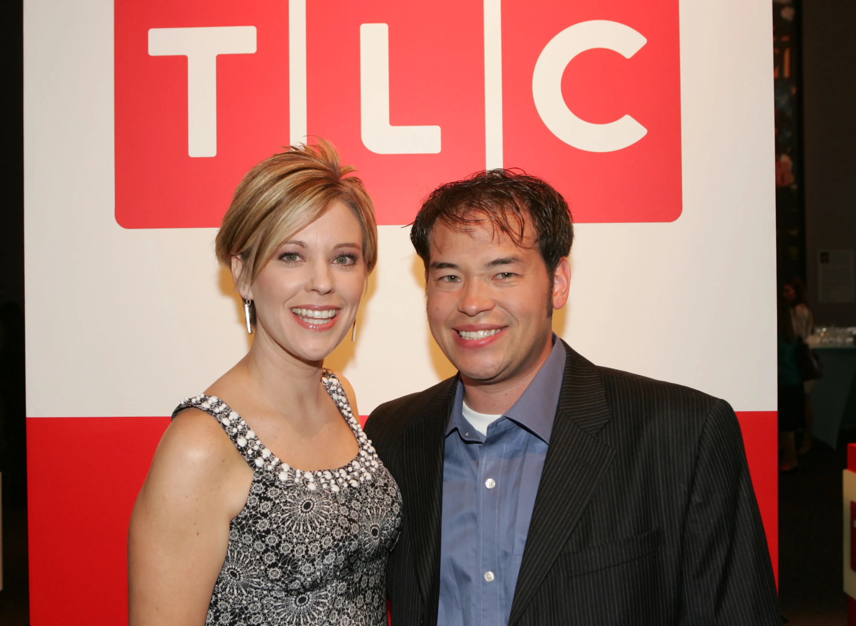 Television personalities Jon and Kate Gosselin pose in front of a TLC logo.