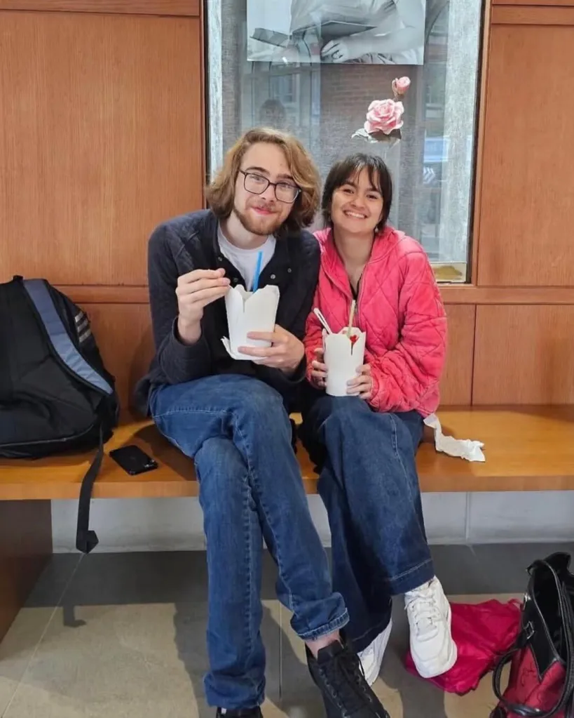 Madison Duren and Julian Harris sitting together on a bench holding takeout boxes.