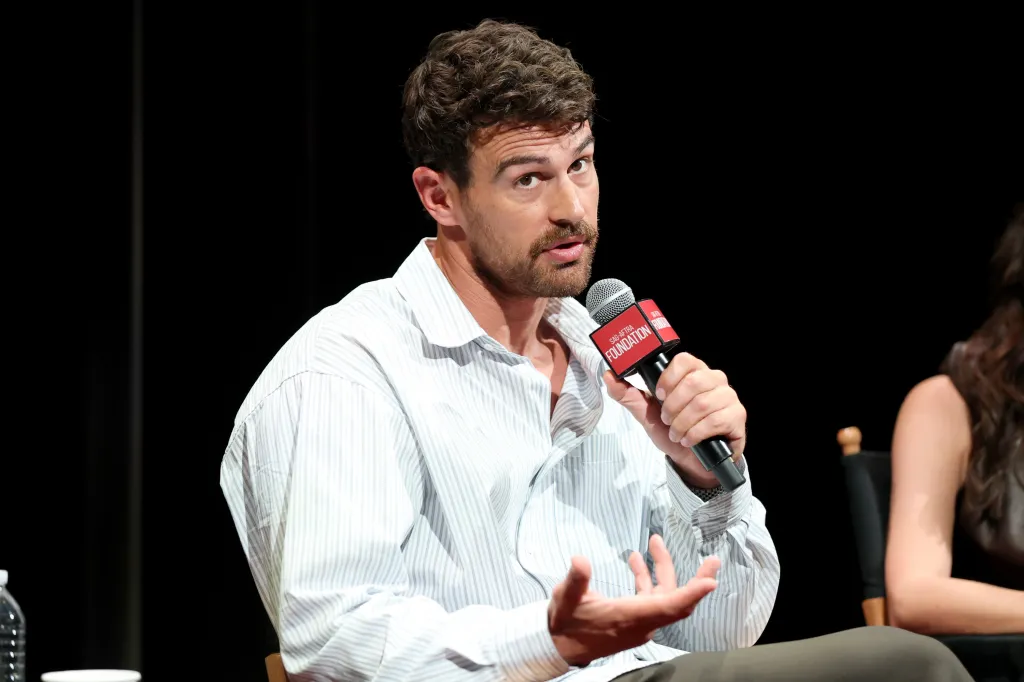 Theo James speaks into a microphone during a conversation for