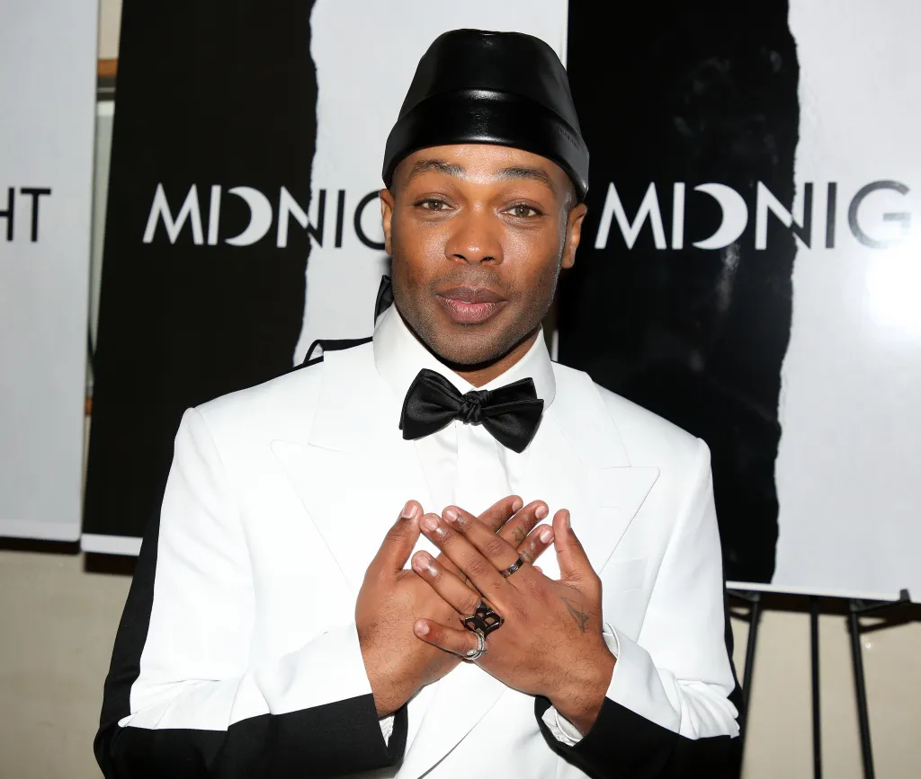 Todrick Hall poses in a white tuxedo and black hat at the opening night gala for the musical 