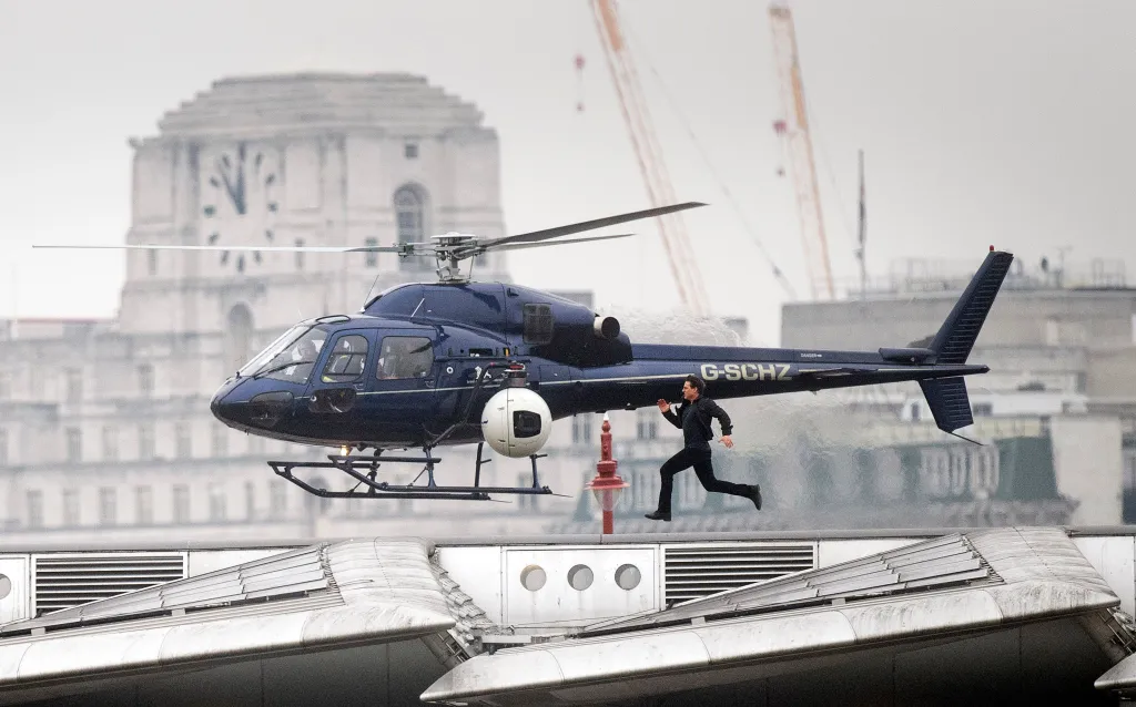 Tom Cruise runs in front of a blue helicopter during filming for a 