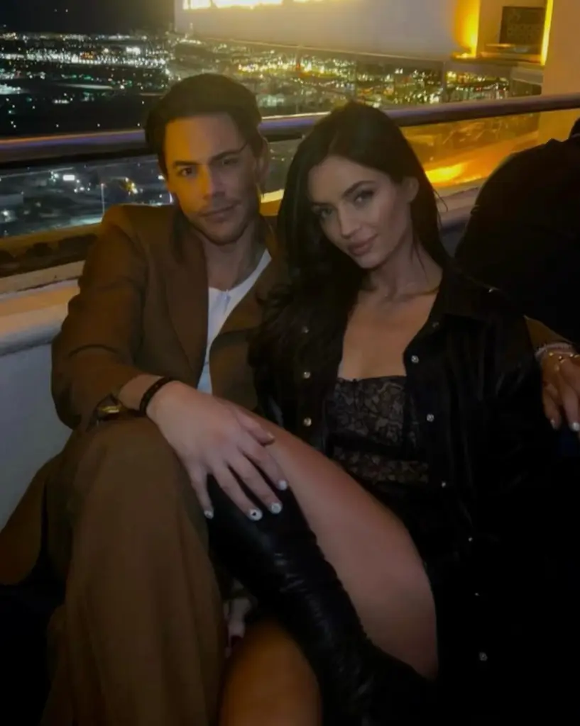 Tom Sandoval and Victoria Robinson posing together with a city view in the background.