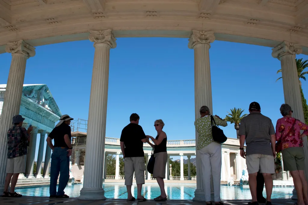 Tourists stand near large marble columns on the edge of the Greco-Roman style Neptune Pool at Hearst Castle.