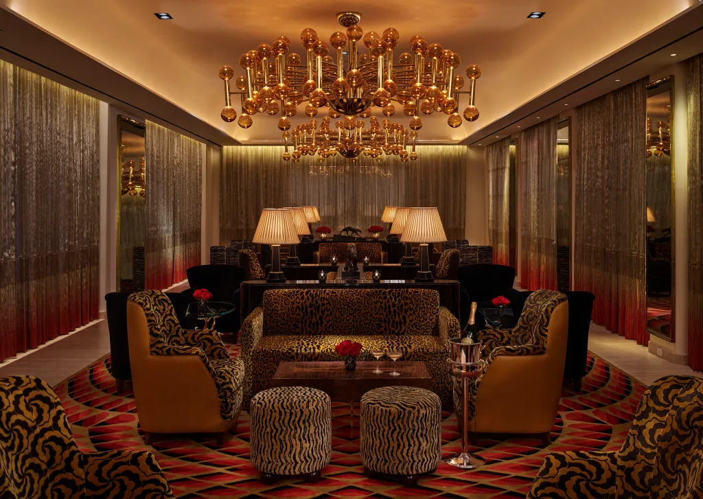 Interior view of Faena New York, featuring a luxurious lounge with leopard-print seating, zebra-striped ottomans, and a large golden chandelier.