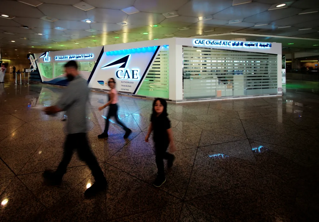Travellers walk past the CAE Oxford ATC registration centre at King Fahd International Airport in Dammam, Saudi Arabia.