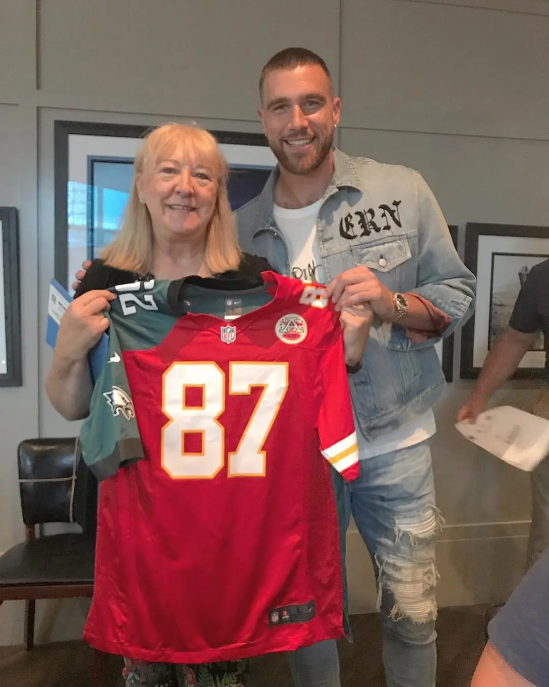 Travis Kelce and his mother Donna holding up his jersey.