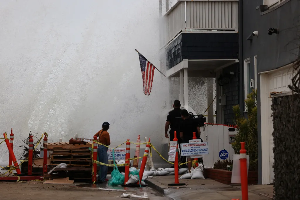 Huge waves crashing against a building along the boardwalk in Long Beach, California.