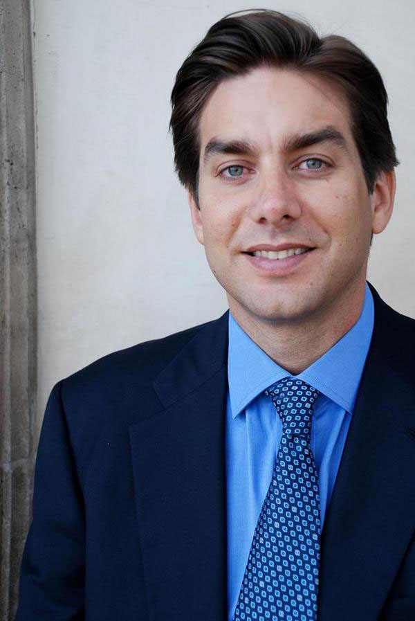 Portrait of Jason Galanis in a blue shirt, patterned tie, and dark jacket.