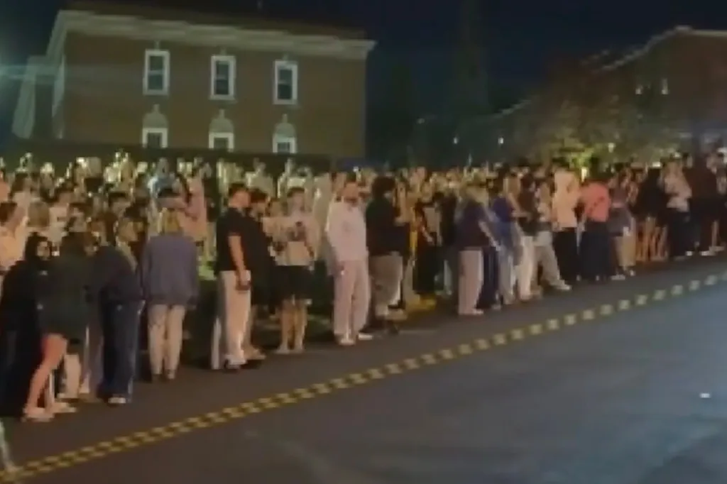 hundreds of onlookers crowding the sidewalks and neighboring yards as police searched the fraternity houses.