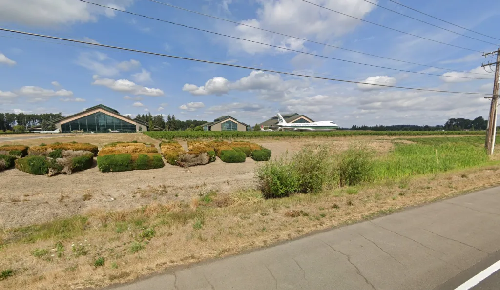 McMinnville Municipal Airport with large buildings and an airplane parked outside.