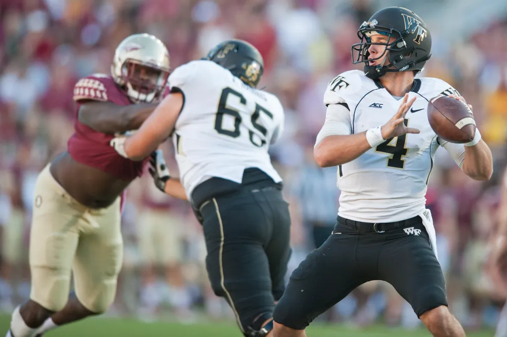Wake Forest Demon Deacons quarterback Tyler Cameron prepares to pass while under pressure from a Florida State defender.