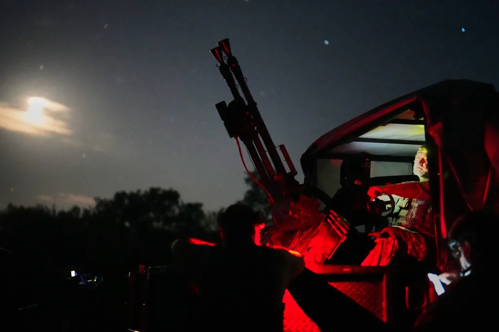 A Ukrainian air defense soldier in a vehicle prepares to repel a drone attack at night.