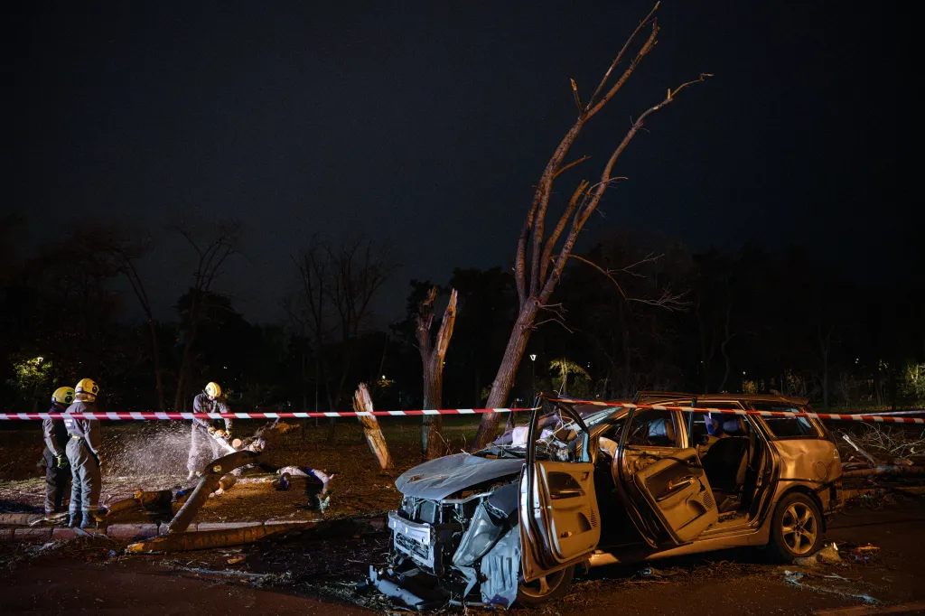 Ukrainian rescuers clear fallen trees near a destroyed car on a road in Kyiv, on Tuesday following a Russian missile strike.