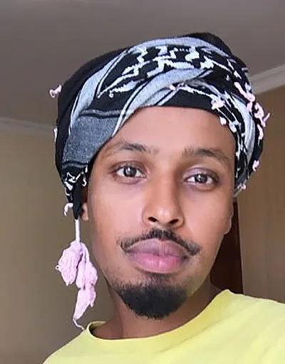 Ahmed Nur Said Elmi wearing a black and gray headscarf and a yellow t-shirt.