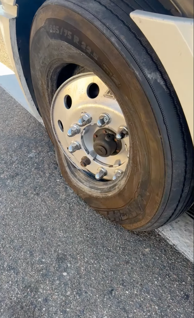A close-up view of a large truck tire melted flat on the asphalt.