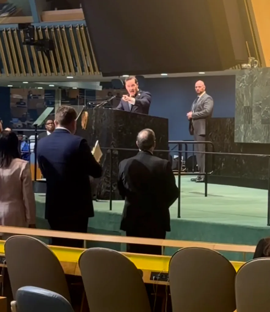 U.S. Ambassador to the United Nations Mike Waltz speaks at a podium in the UN General Assembly hall, pointing forward.