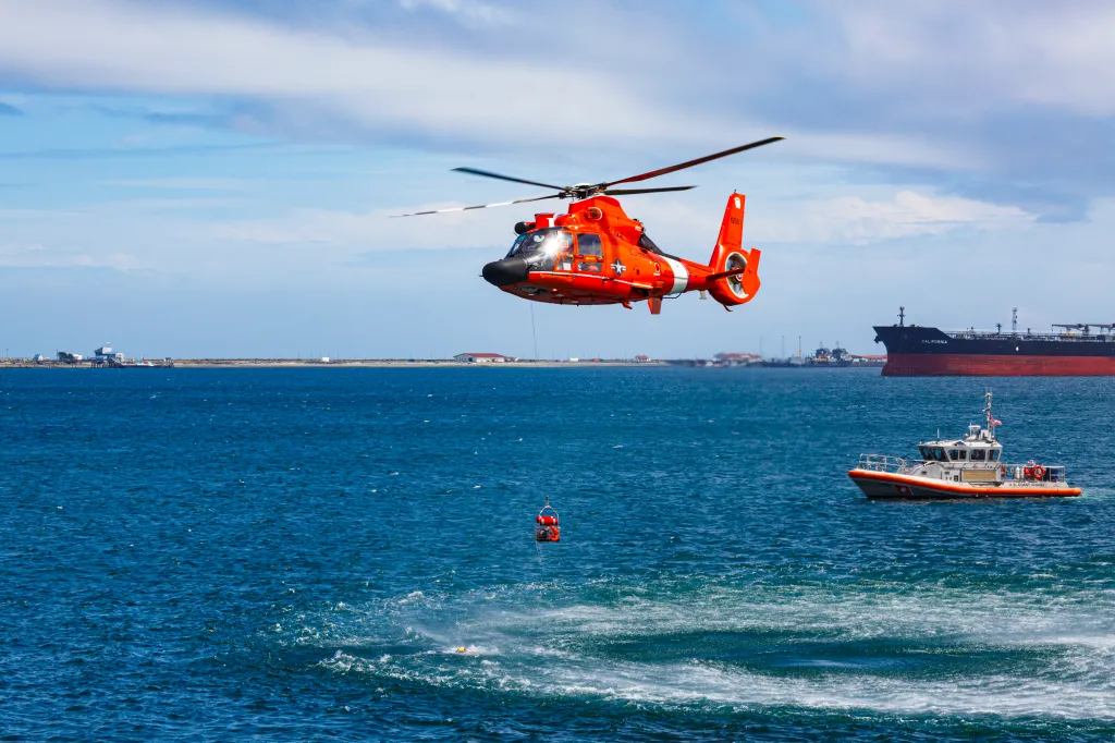 A U.S. Coast Guard helicopter hovers over the water during a sea swimmer rescue demonstration.
