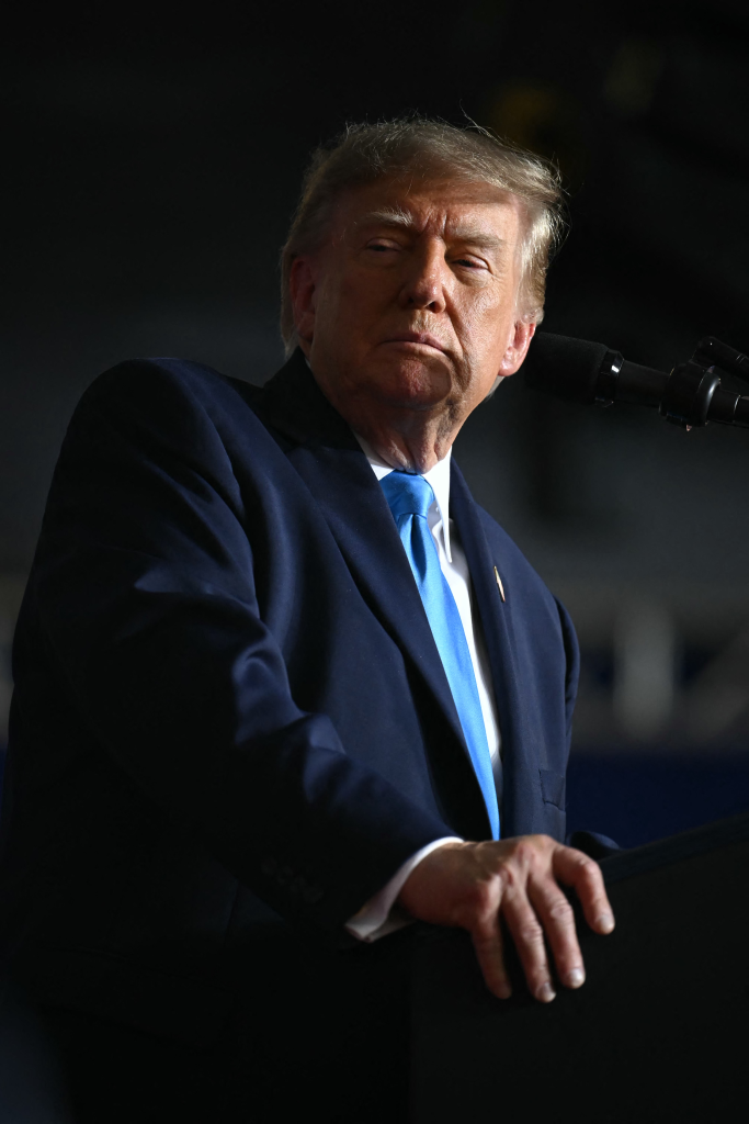 Donald Trump speaks at a campaign rally in a blue suit and tie.