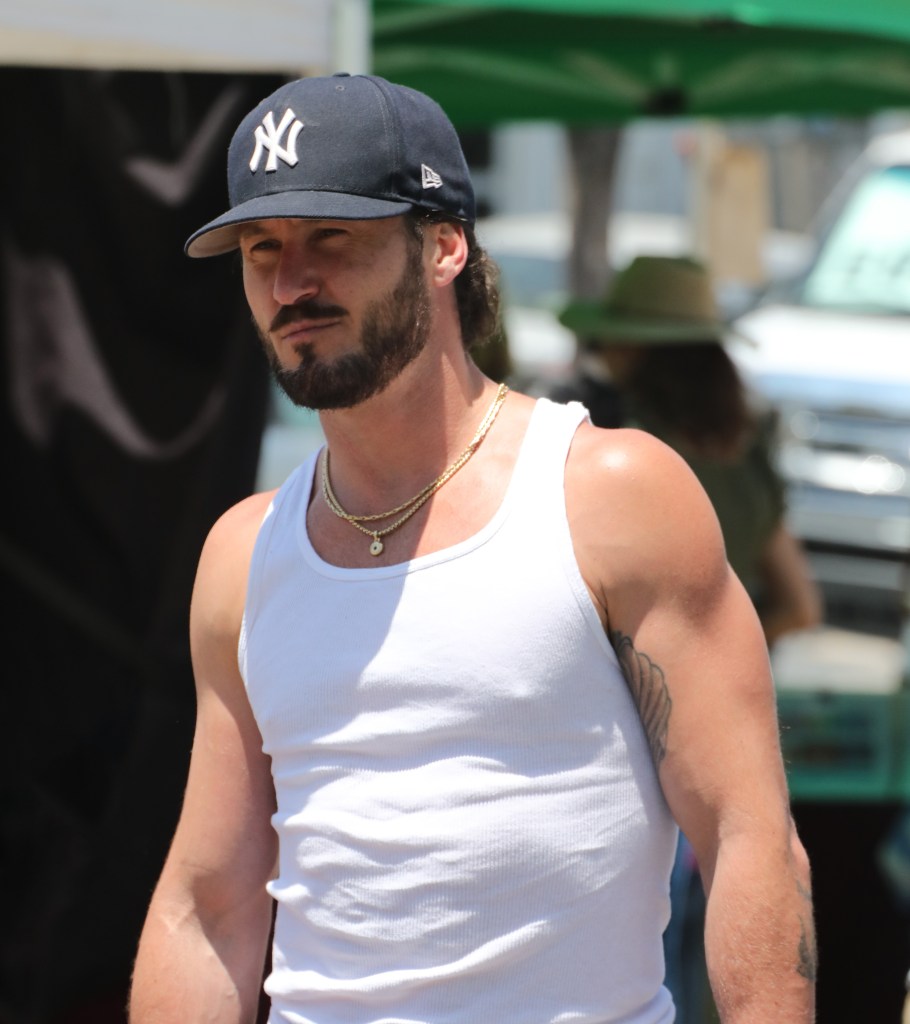 Valentin Chmerkovskiy wearing a white tank top and a baseball cap.