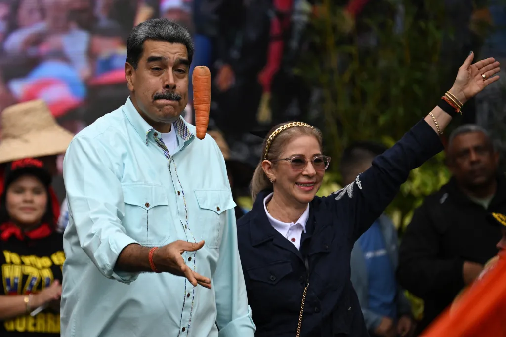 Venezuela's President Nicolas Maduro tosses a carrot into the air upon his arrival with First Lady Cilia Flores at a rally marking the anniversary of the Battle of Santa Ines, in Caracas, on Dec. 10, 2025.