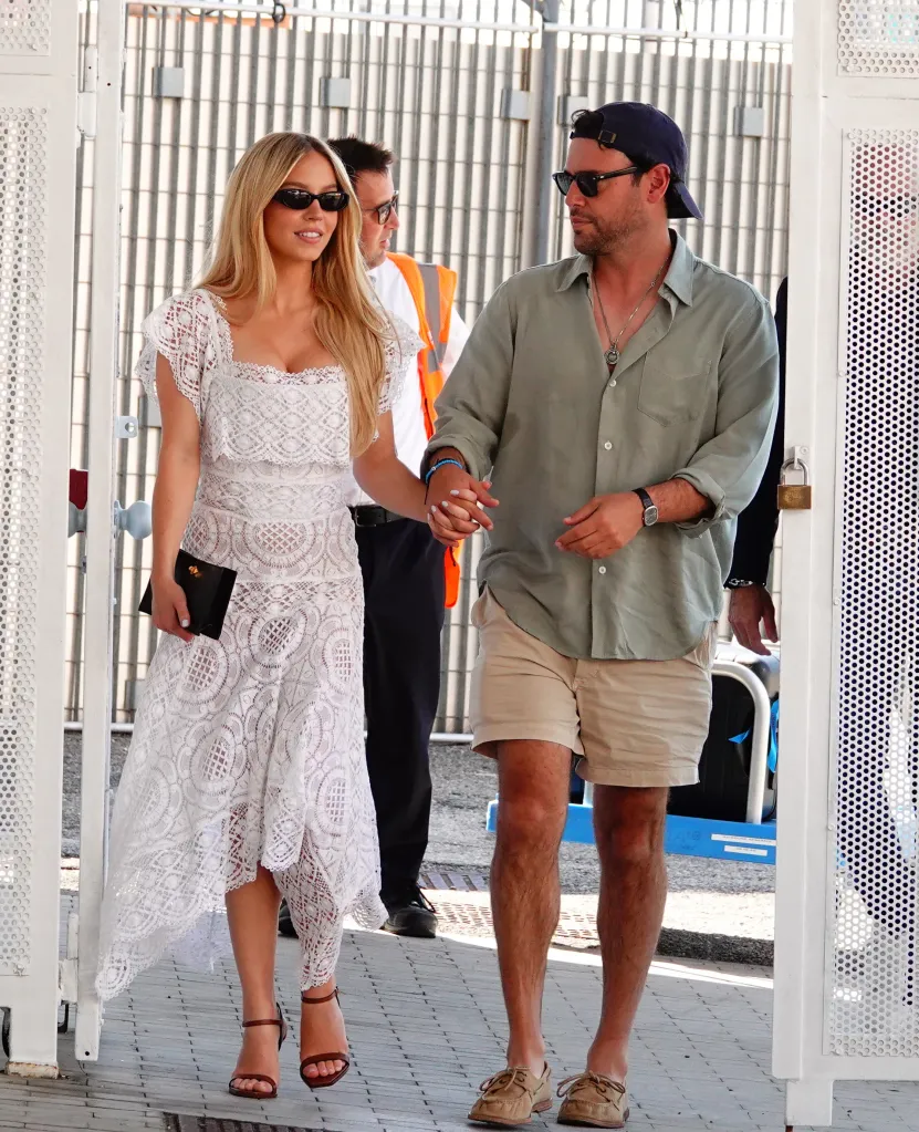 Sydney Sweeney and Scooter Braun holding hands while walking out a door.