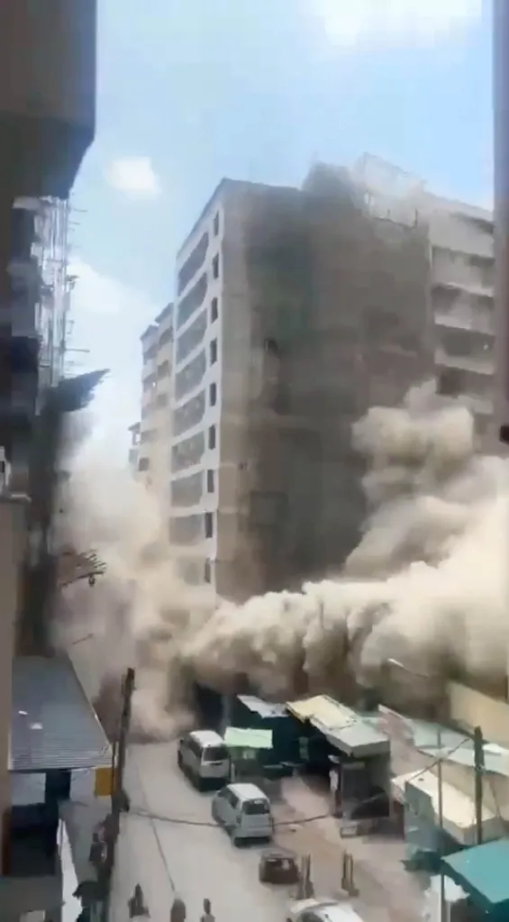 A large multi-story building under construction collapses into a cloud of dust on a narrow street in Nairobi, Kenya.