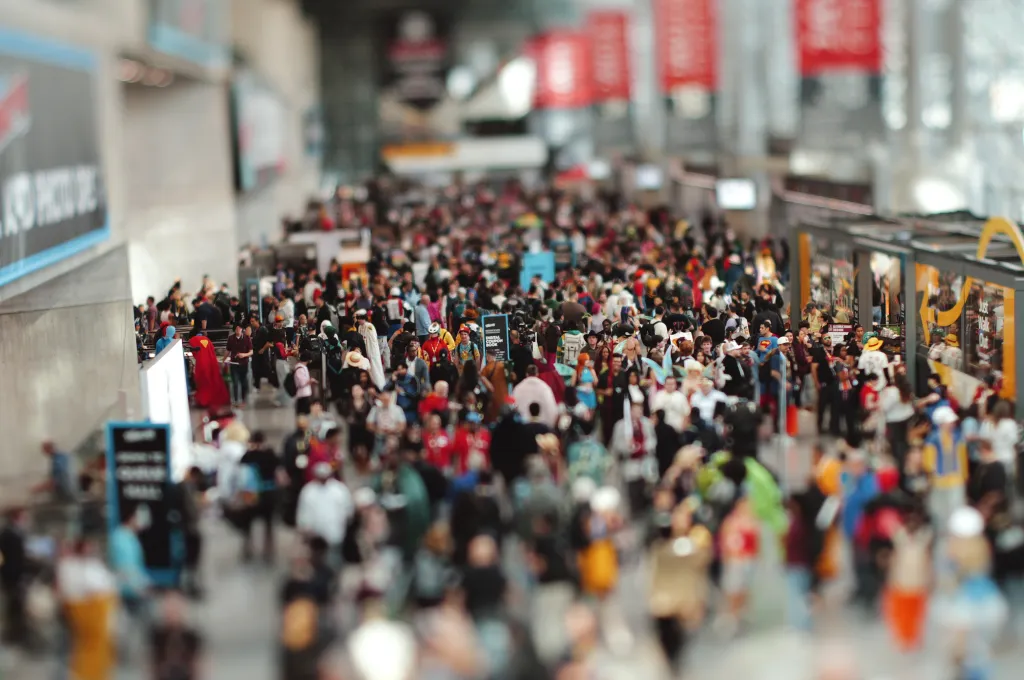 A crowded convention hall filled with attendees in various costumes and cosplay.