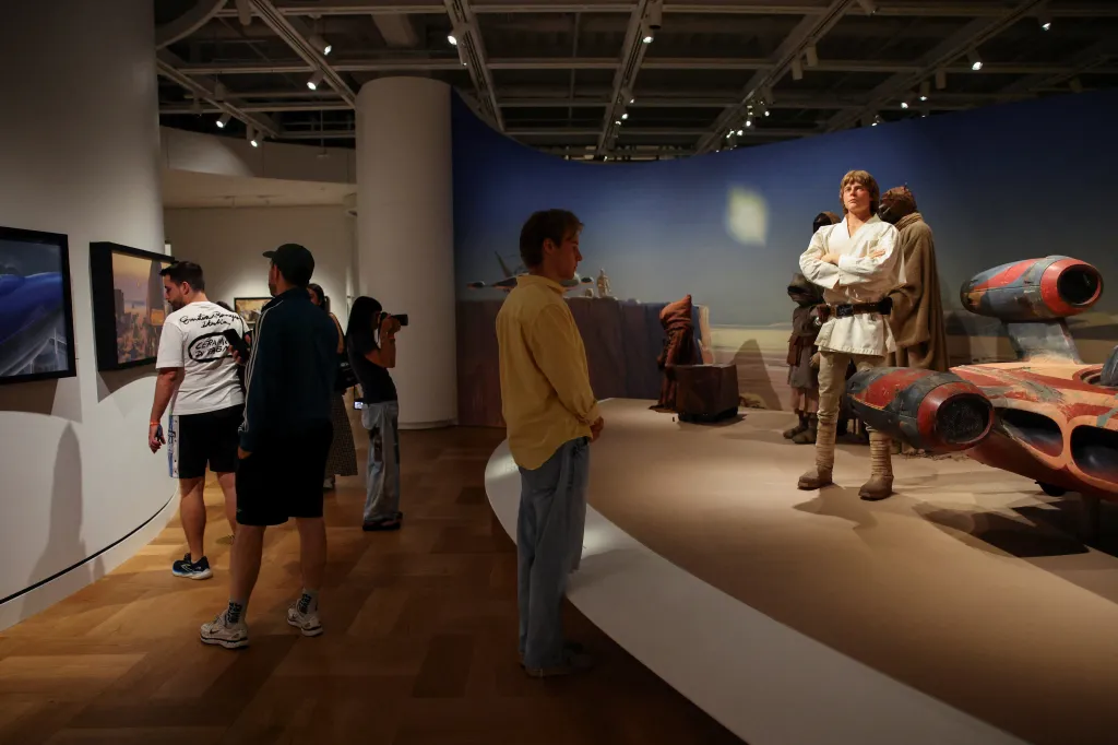 Visitors look at displays including a statue of Luke Skywalker and a landspeeder at the Lucas Museum of Narrative Art.
