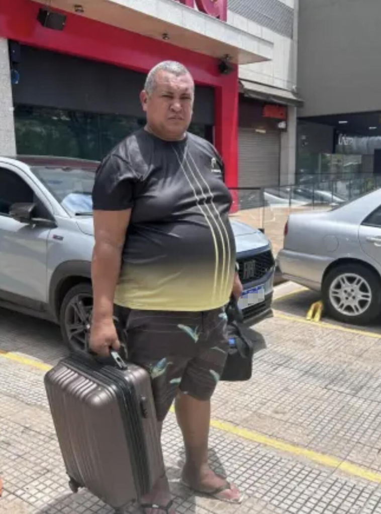 Edimar Rocha Martins, a 49-year-old bricklayer, holding a suitcase in the street.