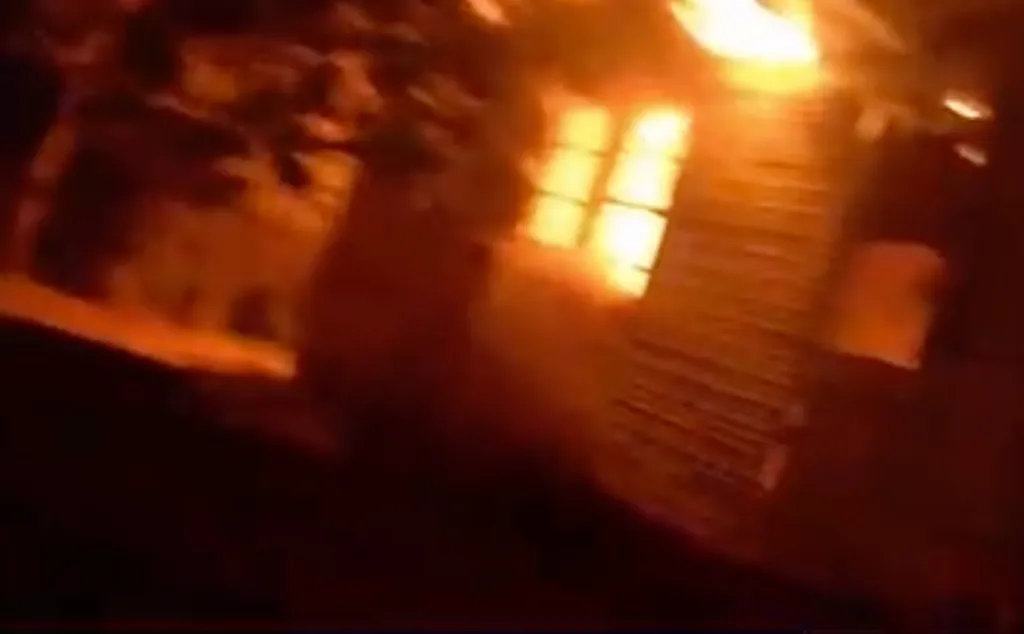 Body camera footage of a house fire at night, showing bright flames engulfing a building.