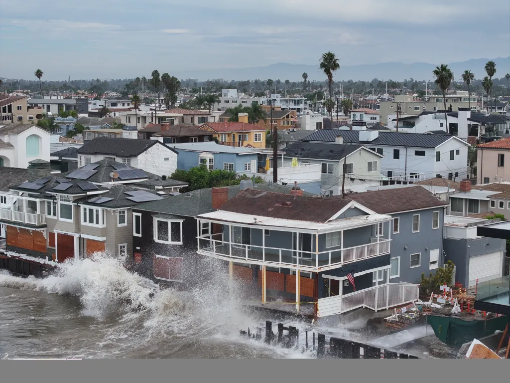 Waves crash against waterfront homes in Long Beach, Calif.